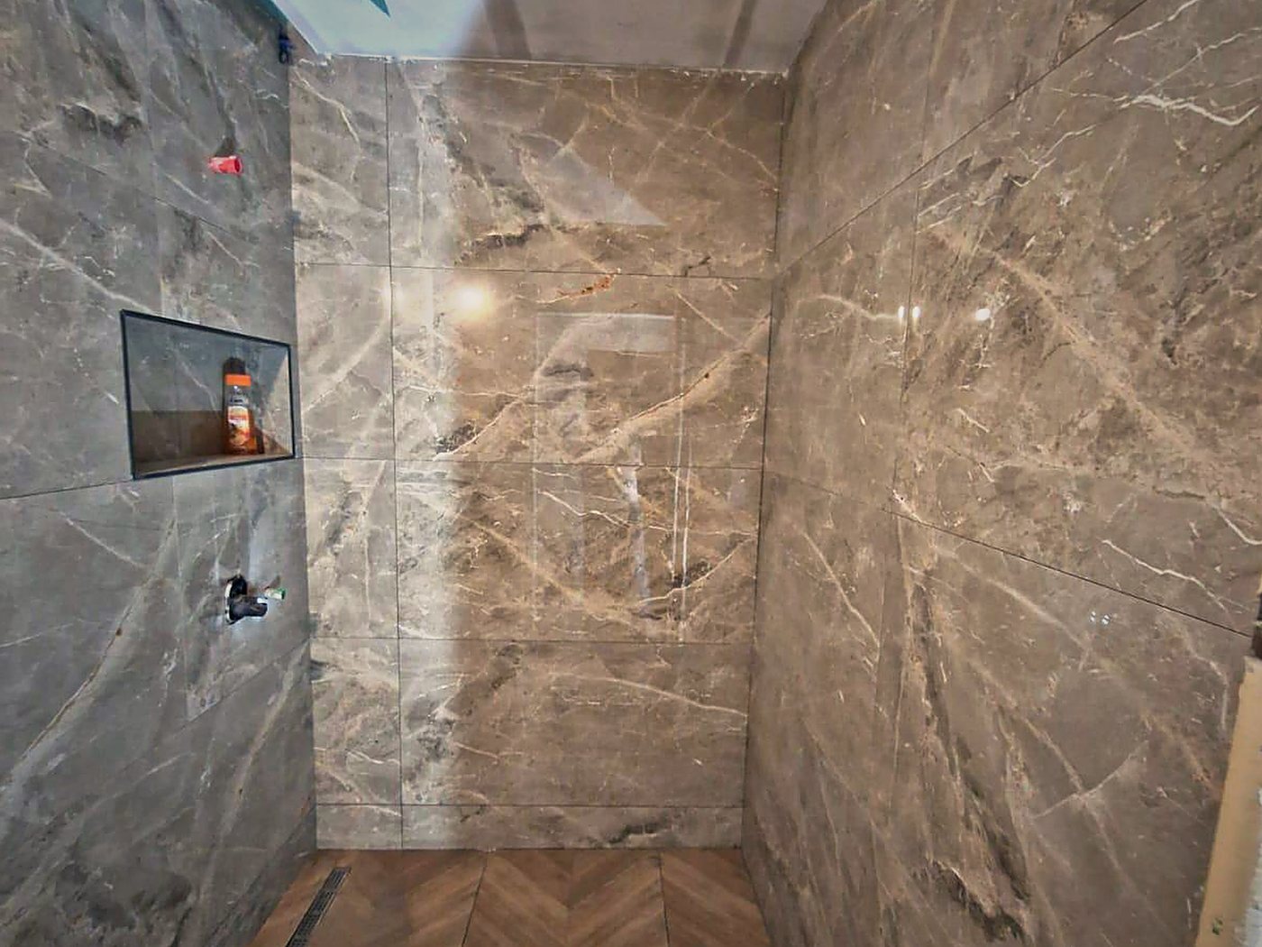 Dușul walk-in, placat cu marmură, cu rigolă în pardoseală